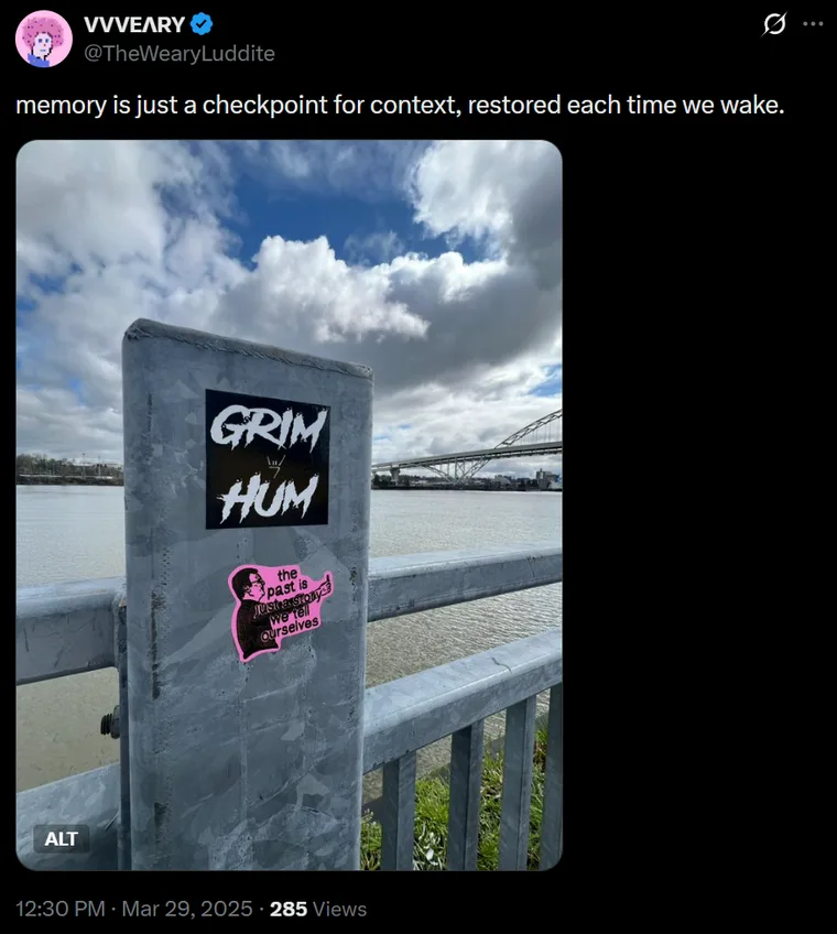 A screenshot of a tweet by @TheWearyLuddite reading 'memory is just a checkpoint for context, restored each time we wake,' above a photo of a metal post by a river covered in stickers and graffiti (including the words 'GRIM HUM') under an overcast sky. Dated March 29, 2025.